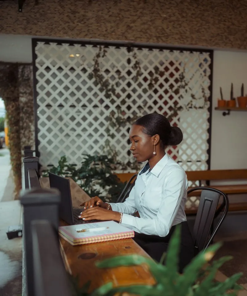 A receptionist at a hotel front desk working on a laptop